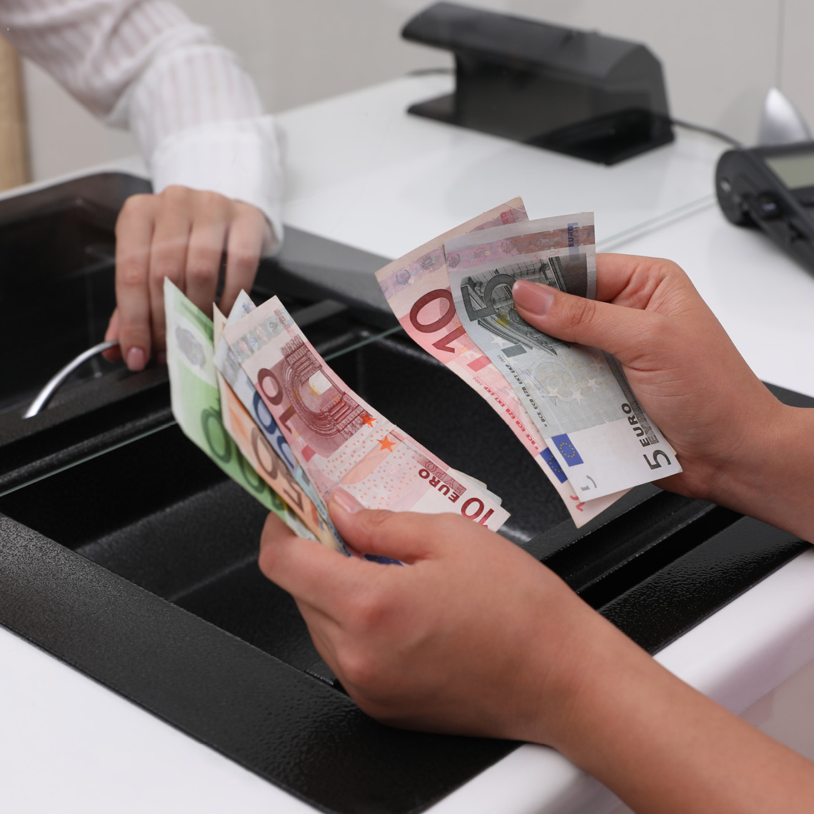 okienko w kantorze i dłonie liczące pieniądze