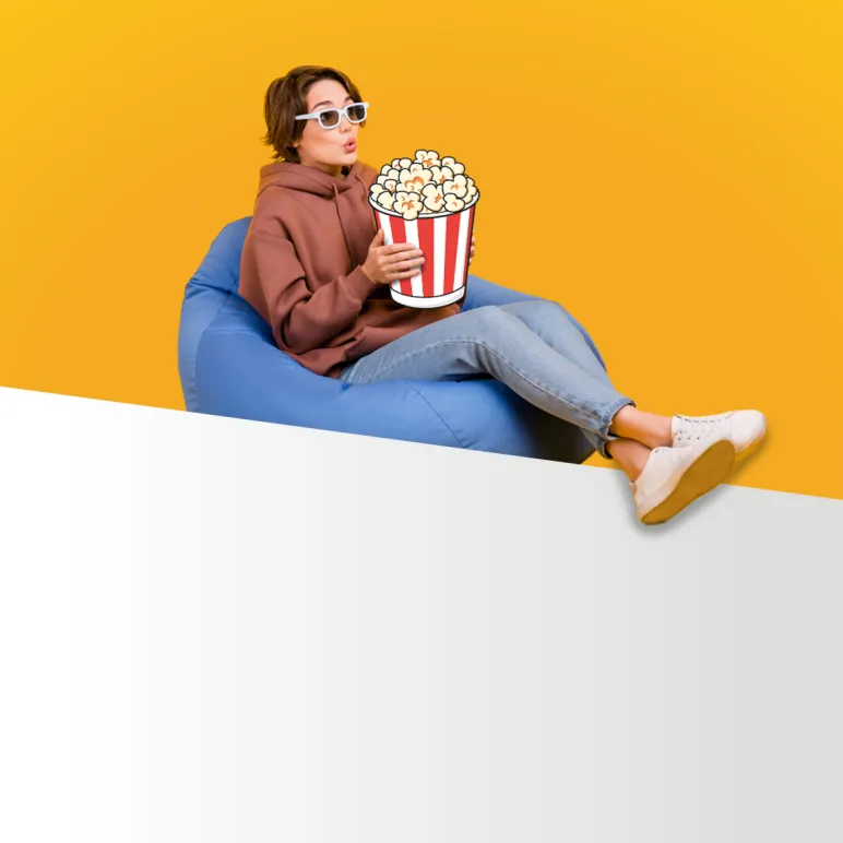 dziewczyna w bluzie siedzi na dmuchanej poduszce i je popcorn